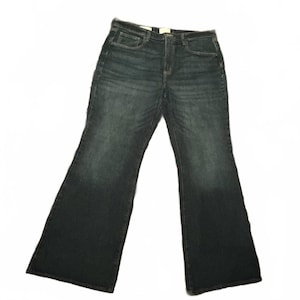 May include: Dark wash denim jeans with a high waist and flared leg. The jeans have classic five-pocket styling and a button and zipper closure. The denim has a slight fade and a subtle texture. A casual, everyday wardrobe staple.