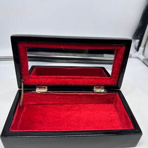 Puede incluir: Caja de madera negra con interior de terciopelo rojo y un peque&ntilde;o espejo dentro de la tapa.