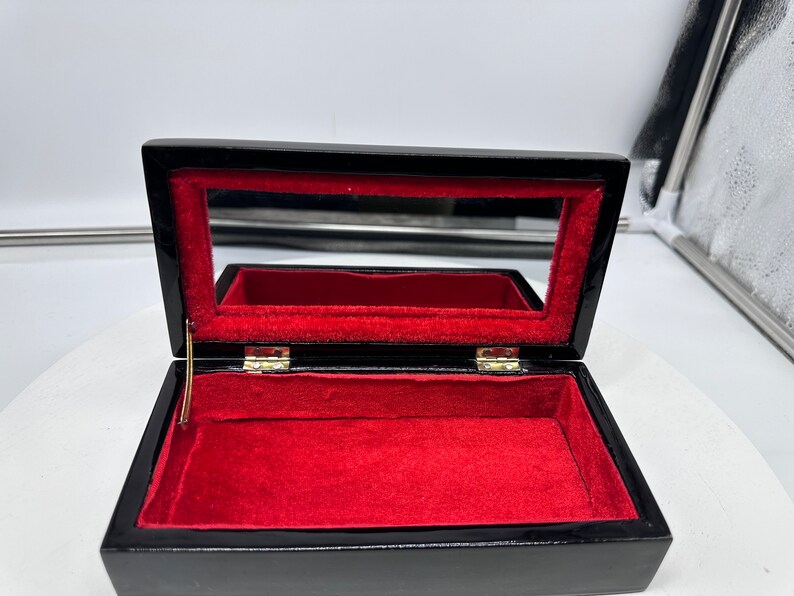 Puede incluir: Caja de madera negra con interior de terciopelo rojo y un peque&ntilde;o espejo dentro de la tapa.