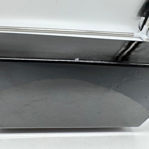 Puede incluir: Un dispositivo electr&oacute;nico negro, rectangular, de bordes curvos, con un acabado brillante.