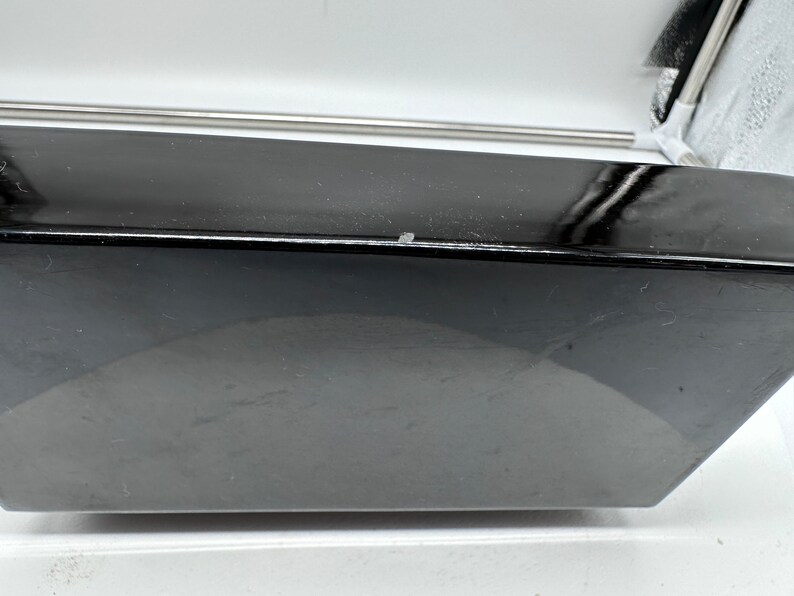 Puede incluir: Un dispositivo electr&oacute;nico negro, rectangular, de bordes curvos, con un acabado brillante.