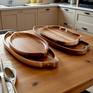 Könnte beinhalten: Eine Sammlung von Serviertabletts aus Holz in verschiedenen Größen und Formen. Die Tabletts sind aus warm getöntem Holz gefertigt und auf einem Holztisch angeordnet. Das Set umfasst ovale und einzigartig geformte Tabletts, ideal zum Servieren von Speisen.