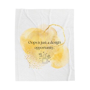 May include: White blanket with a watercolour design featuring yellow and gold accents. The text "Oops is just a design opportunity" is displayed above a nail polish bottle illustration.