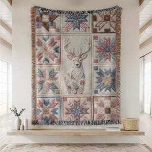 May include: A woven tapestry featuring a deer design in the center, surrounded by patchwork squares in shades of pink, blue, and brown. The tapestry has a fringed edge and is displayed on a wall.