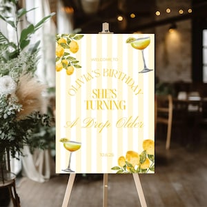 May include: A yellow and white striped welcome sign on an easel. The sign reads "Welcome to Olivia's Birthday, She's Turning A Drop Older" in yellow script. Lemon and cocktail illustrations decorate the sign. The date 10.6.26 is at the bottom.