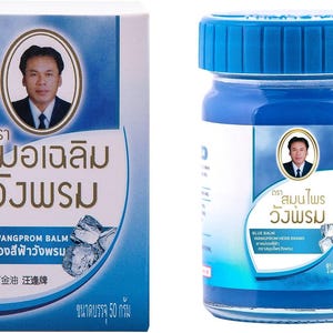 Pode incluir: Um frasco e uma caixa azuis de Blue Wangprom Balm. O frasco tem uma tampa azul e um rótulo com um retrato e texto. A caixa tem um retrato, texto e uma ilustração de cristais de gelo. O bálsamo tem 50 gramas.