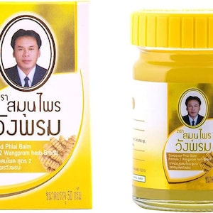 Pode incluir: Um frasco e uma caixa amarelos de bálsamo Compound Phlai. O frasco tem uma tampa amarela e um rótulo branco com texto e a imagem de um homem. A caixa tem uma marca semelhante, incluindo texto em tailandês.
