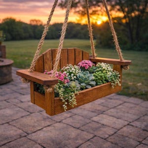 May include: A wooden hanging planter filled with a variety of colorful flowers and succulents. The planter is suspended by thick rope and has a natural wood finish. The background features a sunset over a green lawn.