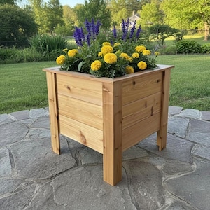May include: A wooden planter box filled with vibrant yellow marigolds and purple salvia flowers. The rectangular planter is made of light brown wood and sits on four sturdy legs, perfect for a garden or patio.