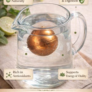 May include: A spherical copper ball submerged in a clear glass pitcher filled with water. Text labels state: Purifies Water Naturally, Boosts Immunity & Digestion, Rich in Antioxidants, Supports Energy & Vitality, and 100% Pure Copper Ball for Water Purification.