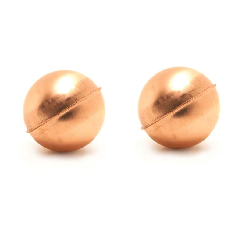 May include: A pair of spherical copper-toned stud earrings. Each earring features a smooth, polished surface with a distinct horizontal seam running across the center of the round shape, creating a simple and uniform metallic appearance.