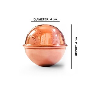 May include: A polished copper-colored spherical object with a horizontal seam around the center. The object features a reflective surface and is labeled with a diameter of 1.57 inches and a height of 1.57 inches, indicating its dimensions.
