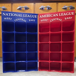 May include: A blue National League display rack and a red American League display rack, each featuring fifteen square compartments arranged in five rows and three columns, with the league name and division labels West, Central, and East printed.