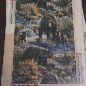 May include: Diamond painting kit featuring a detailed image of bears in a natural setting. The artwork is composed of small, sparkling diamond-shaped pieces. The kit includes the item number GI231 and the size 30x40.