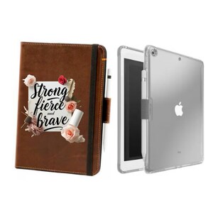 May include: A brown leather journal with the words "Strong, Fierce, and Brave" and floral accents. Next to it is a clear iPad case with an iPad and a white stylus.