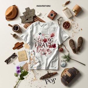 May include: White t-shirt with the words "STRONG BRAVE" in a floral design. The image includes a brown hat, sunglasses, a camera, shoes, and other decorative items. The word "POP" is at the bottom.