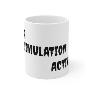 Può includere: Tazza in ceramica bianca con testo nero "SIMULATION ACTIV". La tazza è cilindrica e ha una finitura lucida. Il testo è in un carattere in grassetto e stilizzato.