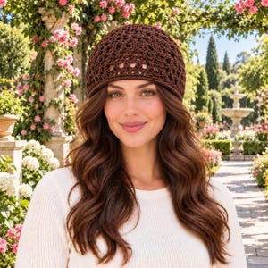 May include: A dark brown crochet beanie featuring a repeating geometric pattern with small openwork details throughout the fabric. The hat has a rounded crown and a solid, tightly stitched band around the bottom edge, providing a textured appearance.