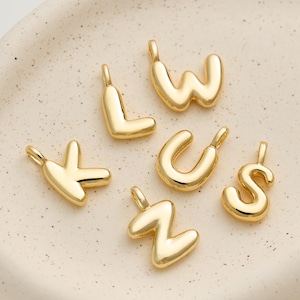 Peut inclure: Six breloques dorées en forme de lettres : K, L, S, U, W et Z. Chaque breloque possède une boucle en haut pour l'attacher à une chaîne ou un bracelet. Les lettres sont dans une police arrondie, de style bulle.