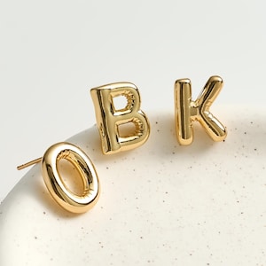 May include: A white ceramic mug with a black handle and the text "But First, Coffee" in a bold, black font. The mug is set against a blurred background, suggesting a cosy setting.