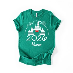 A green t-shirt with a white graphic design featuring a castle and fireworks, along with the text "2020 Name" printed on it.