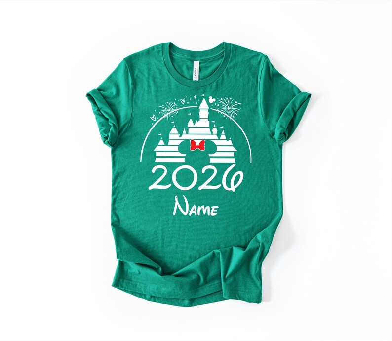 A green t-shirt with a white graphic design featuring a castle and fireworks, along with the text "2020 Name" printed on it.