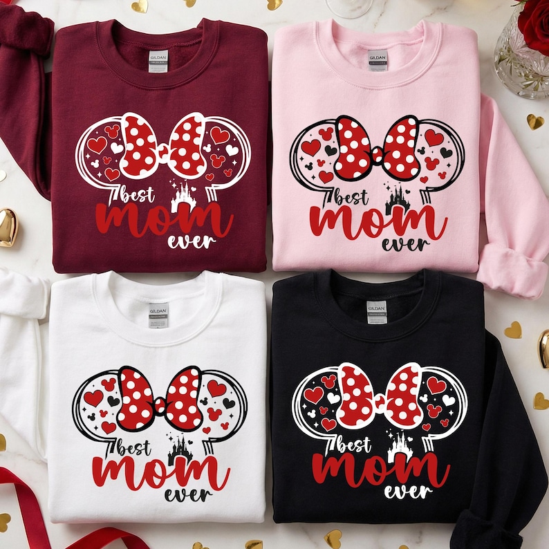 May include: Four sweatshirts in burgundy, pink, white, and black. Each has a design with a red polka-dot bow, hearts, and the text "Best Mom Ever" in red. The design is framed by Mickey Mouse ears.