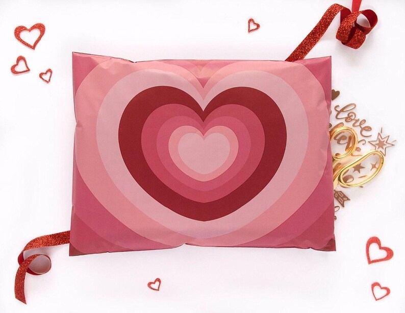 a pink pillow with a heart-shaped design, surrounded by red hearts and a red ribbon.