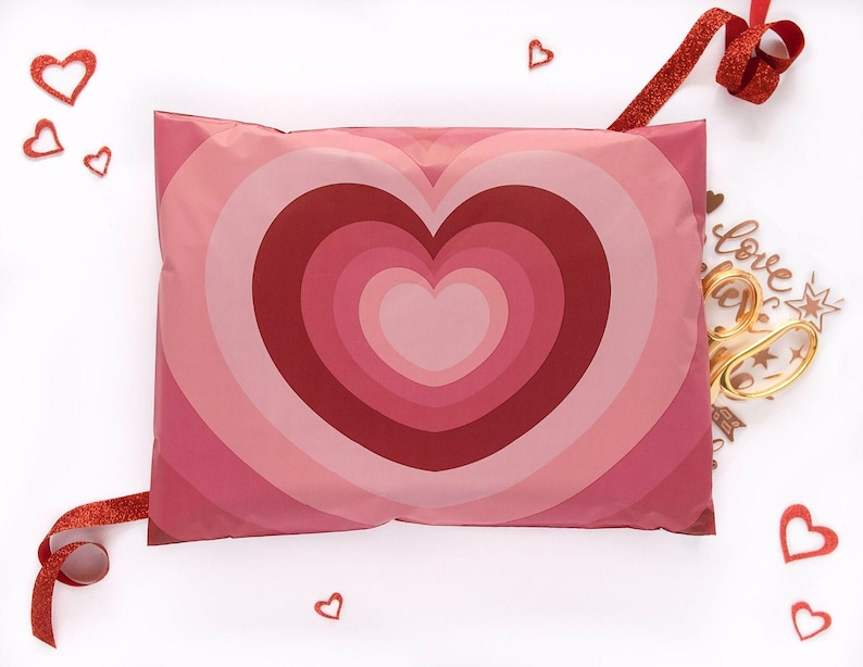 May include: A pink and red heart-patterned package with a red ribbon and heart-shaped decorations. The package features concentric heart shapes in varying shades of pink and red, creating a visually appealing design. Ideal for Valentine's Day or romantic gifts.