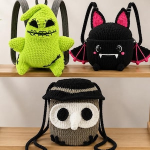 May include: Three crochet backpacks shaped like characters. One is a bright green figure with stitched facial features, one is a black bat with pink inner ears and wings, and one is a gray and white owl with a black hat and large round eyes.