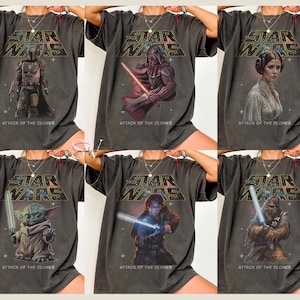 May include: Six dark gray t-shirts featuring Star Wars characters: The Mandalorian, Darth Vader, Princess Leia, Yoda, Anakin Skywalker, and Chewbacca. Each shirt has the Star Wars logo and "Attack of the Clones" text.