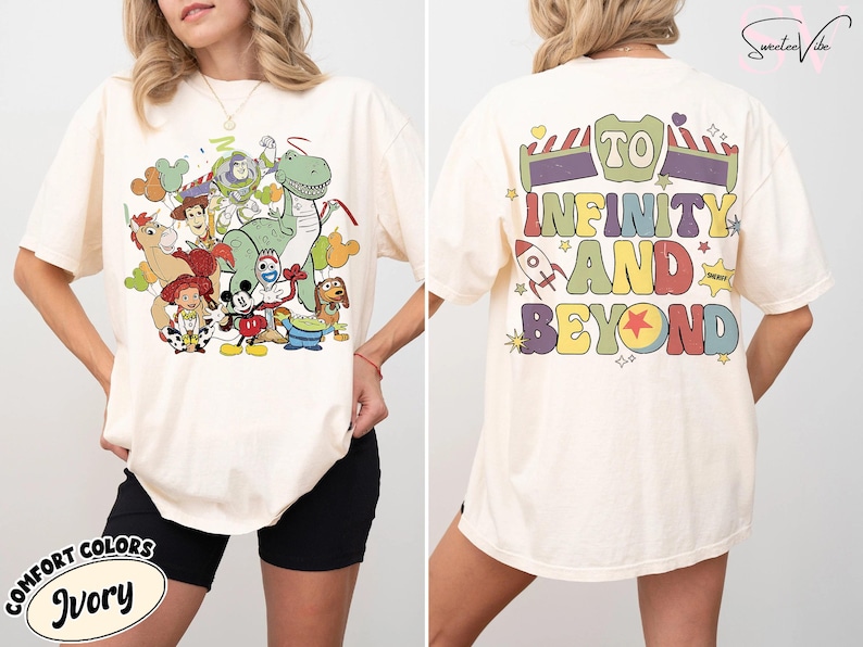Op de afbeelding: Ivoor kleurig T-shirt met een kleurrijke afbeelding van animatiefiguren, waaronder een groene dinosaurus, Woody, Buzz Lightyear en Mickey Mouse. De achterkant van het shirt toont de zin "TO INFINITY AND BEYOND" in een retro lettertype, met een raket en sterren.