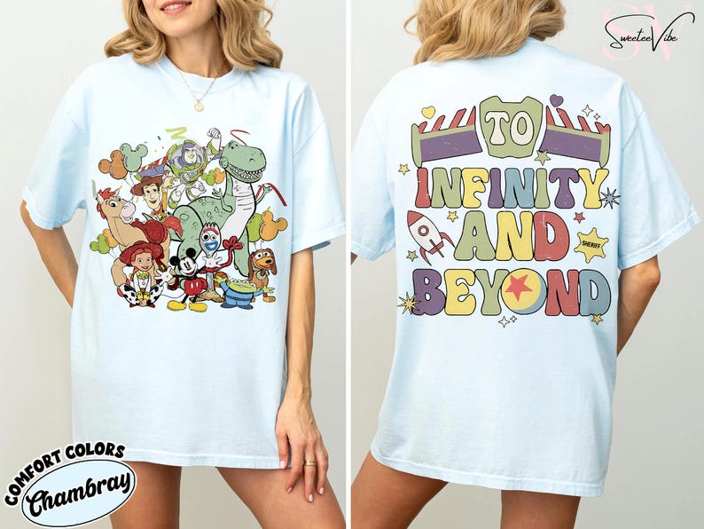 Op de afbeelding: Lichtblauw T-shirt met een kleurrijke afbeelding van Toy Story-personages op de voorkant. De achterkant van het shirt toont de zin "To Infinity and Beyond" in een retro lettertype. Het shirt is gemaakt van Comfort Colors Chambray stof.