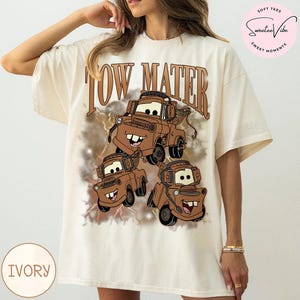 K&ouml;nnte beinhalten: Elfenbeinfarbenes T-Shirt mit einem Aufdruck der Figur Hook aus dem Film Cars. Das Design zeigt den Text "TOW MATER" in Braun &uuml;ber dem Cartoon-Bild von Hook. Das T-Shirt hat eine lockere Passform und ist aus weichem Material.