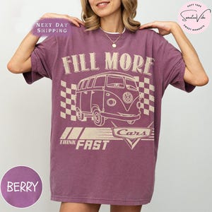 Puede incluir: Camiseta color bayas con un gr&aacute;fico de una furgoneta vintage y las palabras "FILL MORE" encima. Debajo de la furgoneta est&aacute;n las palabras "THINK FAST" y "Cars". La camiseta tiene un corte holgado y mangas cortas.