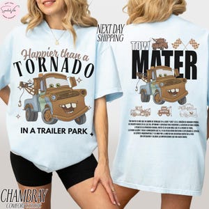 Puede incluir: Camiseta azul claro con una imagen de dibujos animados de Tow Mater de la pel&iacute;cula Cars, con el texto "Happier than a Tornado" y "In a Trailer Park". La parte posterior de la camiseta tiene un dise&ntilde;o a juego con el texto "Tow Mater".