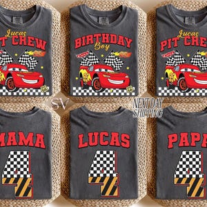 May include: Gray t-shirts with various designs. Some shirts say "Lucas PIT CREW" with a red race car graphic. Others say "BIRTHDAY Boy", "MAMA", "LUCAS", and "PAPA" with a number 4 graphic. The shirts are displayed on a woven surface.
