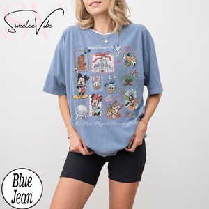 Puede incluir: Camiseta azul claro con un gr&aacute;fico colorido de personajes y lugares emblem&aacute;ticos de Disney. El dise&ntilde;o incluye Mickey Mouse, Minnie Mouse, Donald Duck y Chip y Chop. Tambi&eacute;n se ve el texto "Walt Disney World" y "2026".