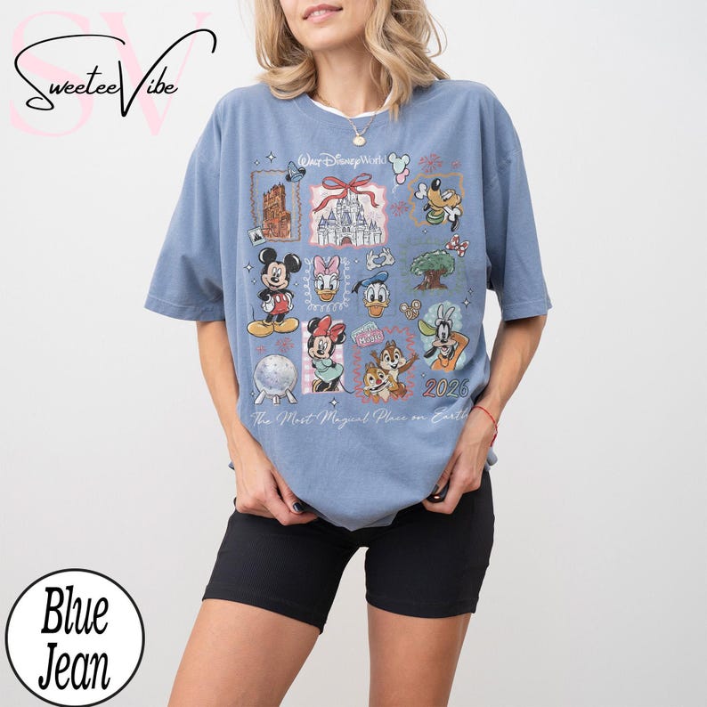 Puede incluir: Camiseta azul claro con un gr&aacute;fico colorido de personajes y lugares emblem&aacute;ticos de Disney. El dise&ntilde;o incluye Mickey Mouse, Minnie Mouse, Donald Duck y Chip y Chop. Tambi&eacute;n se ve el texto "Walt Disney World" y "2026".