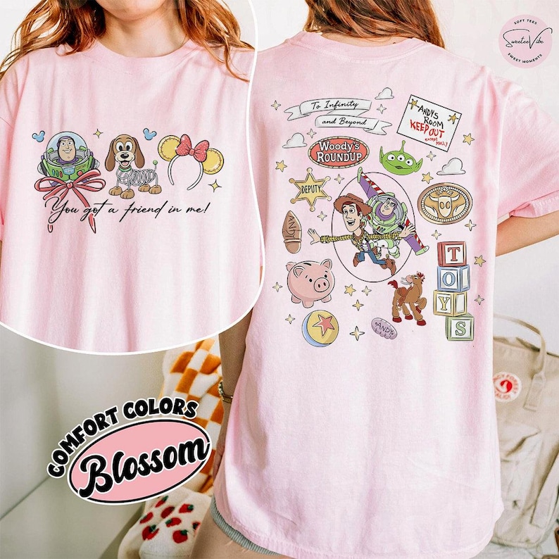 May include: Pink t-shirt featuring Toy Story characters and the phrase "You got a friend in me!" on the front. The back of the shirt has additional Toy Story graphics and the text "To Infinity and Beyond".