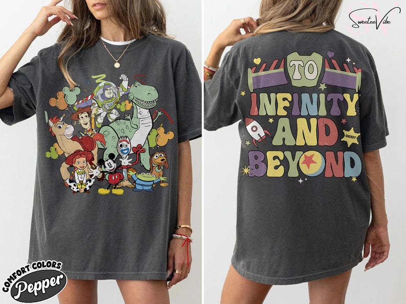Op de afbeelding: Donkergrijs t-shirt met een kleurrijke afbeelding van Toy Story-personages op de voorkant. De achterkant van het shirt heeft de tekst "To Infinity and Beyond" in een retro lettertype. Het shirt is gelabeld "Comfort Colors Pepper".