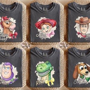 Puede incluir: Seis camisetas de color gris antracita con personajes de dibujos animados populares. Cada camiseta muestra un personaje diferente: Bullseye el caballo, Jessie, Woody, Buzz Lightyear, Rex y Slinky Dog. Cada personaje est&aacute; rodeado por una forma blanca similar a una nube.