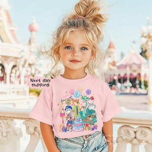 Peut inclure: T-shirt rose avec un motif d'anniversaire de dessin anim&eacute; avec des personnages d'animaux, un g&acirc;teau et des ballons. Le t-shirt porte le texte "Next day shipping" sur le c&ocirc;t&eacute; gauche. Le t-shirt est port&eacute; par une jeune fille.