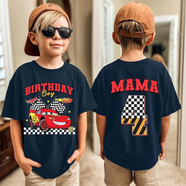 May include: Navy blue t-shirt with a graphic of a red race car and the text "BIRTHDAY Boy 95". The back of the shirt has the word "MAMA" and a checkered number 4. The shirt is for a child.