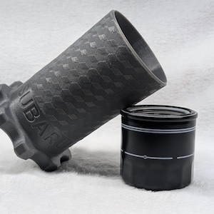 May include: A dark gray Subaru oil filter wrench and a black oil filter. The wrench has a textured hexagonal pattern and the word "SUBARU" is visible. The oil filter is black with two white stripes.
