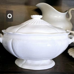 May include: White ceramic serving dish with a lid. The dish has a fluted edge and a decorative design on the lid.