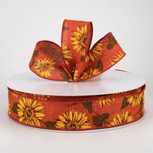 May include: A roll of 2.5 inch wide red burlap ribbon with a sunflower print. The ribbon is decorated with yellow sunflowers and green leaves.