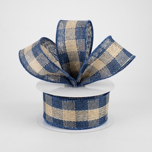 May include: A roll of blue and beige checkered ribbon with a burlap texture. The ribbon is on a white spool.