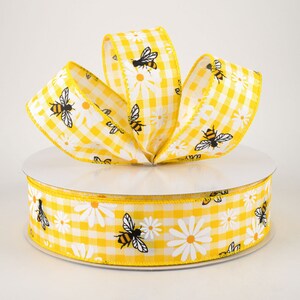 May include: Yellow gingham ribbon with white daisies and black bees. The ribbon is on a spool.