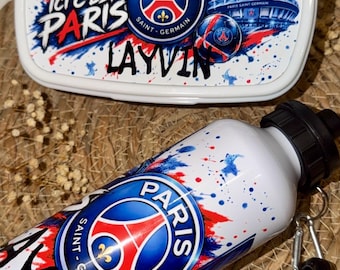 Peut inclure: Une boîte à lunch en plastique blanc et une gourde en métal blanc assortie arborant le logo de l'équipe de football Paris Saint-Germain, des éclaboussures de peinture bleue et rouge, la tour Eiffel, le texte "ICI C'EST PARIS" et le nom "LAYVIN".